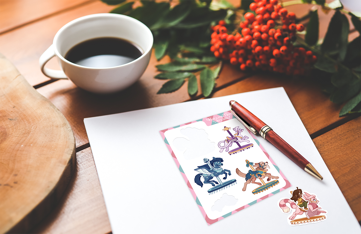 Cup of coffee, pen, and a carousel-themed sticker sheet on a wooden table with leaves and berries.